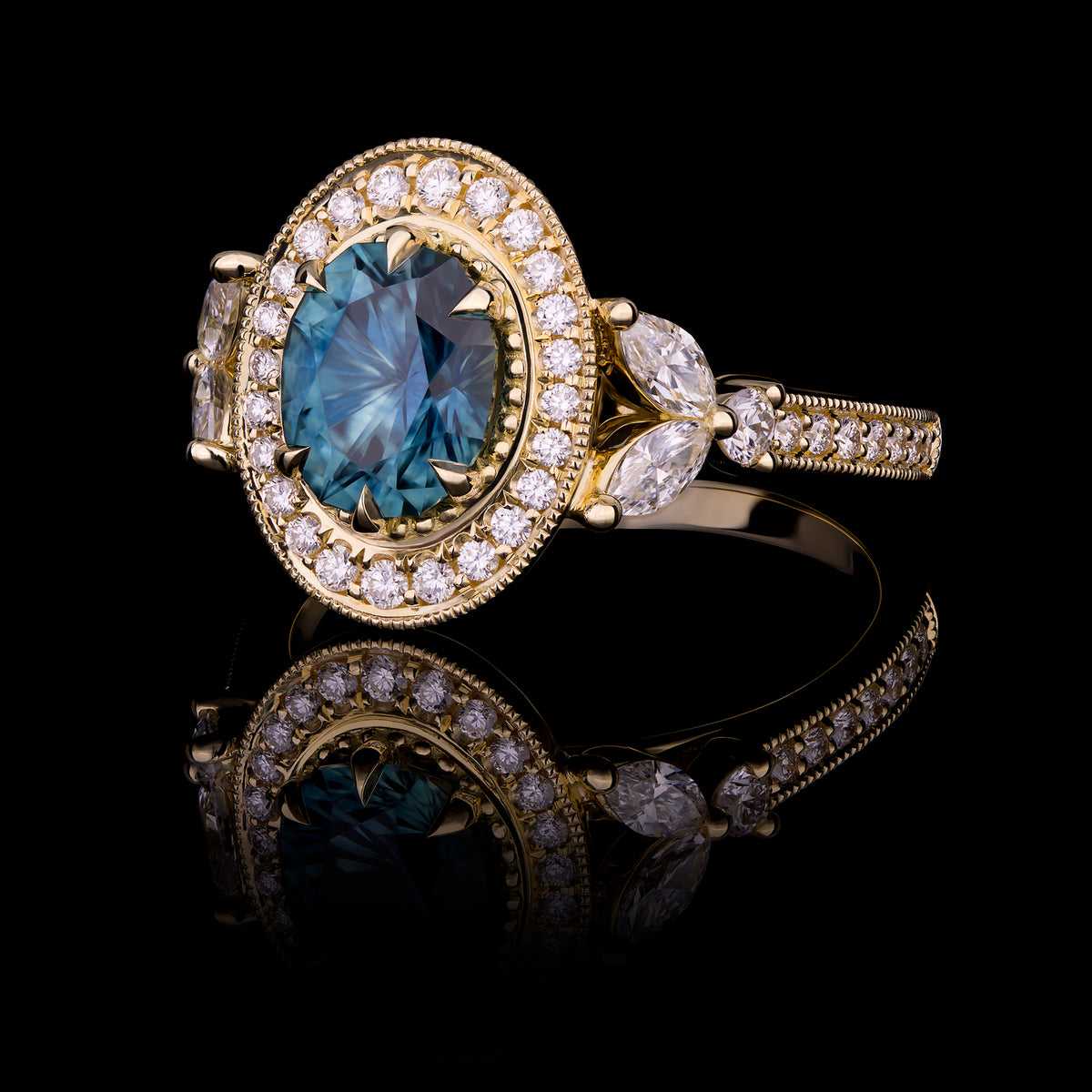 Custom blue sapphire with diamond halo ring, in yellow gold and mil grain detail.