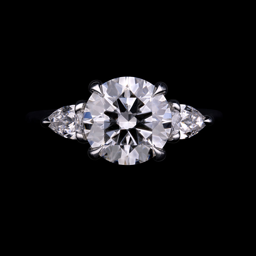 A classic three-stone diamond ring featuring a large round brilliant-cut center stone flanked by two smaller marquise-cut stones.