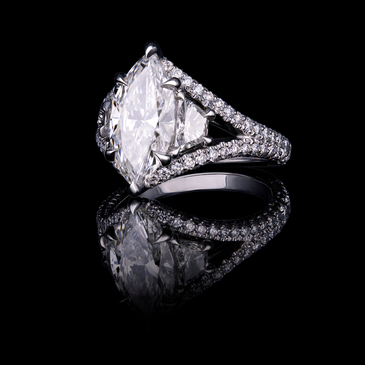 A marquise-cut diamond ring in a three-stone setting with a bypass pavé band.