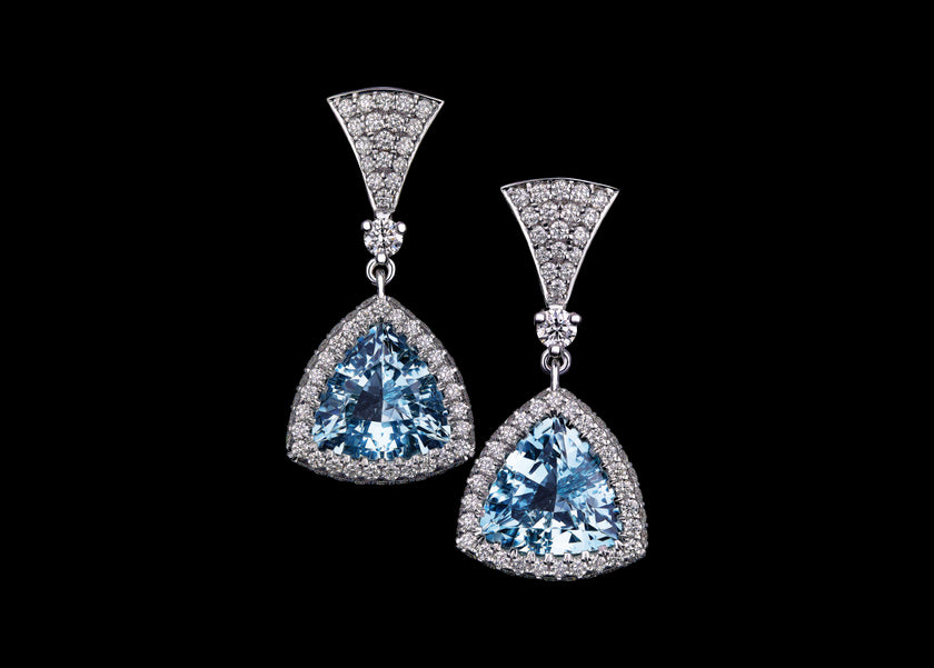 A pair of white gold drop earrings featuring large triangular aquamarines surrounded by a diamond halo.