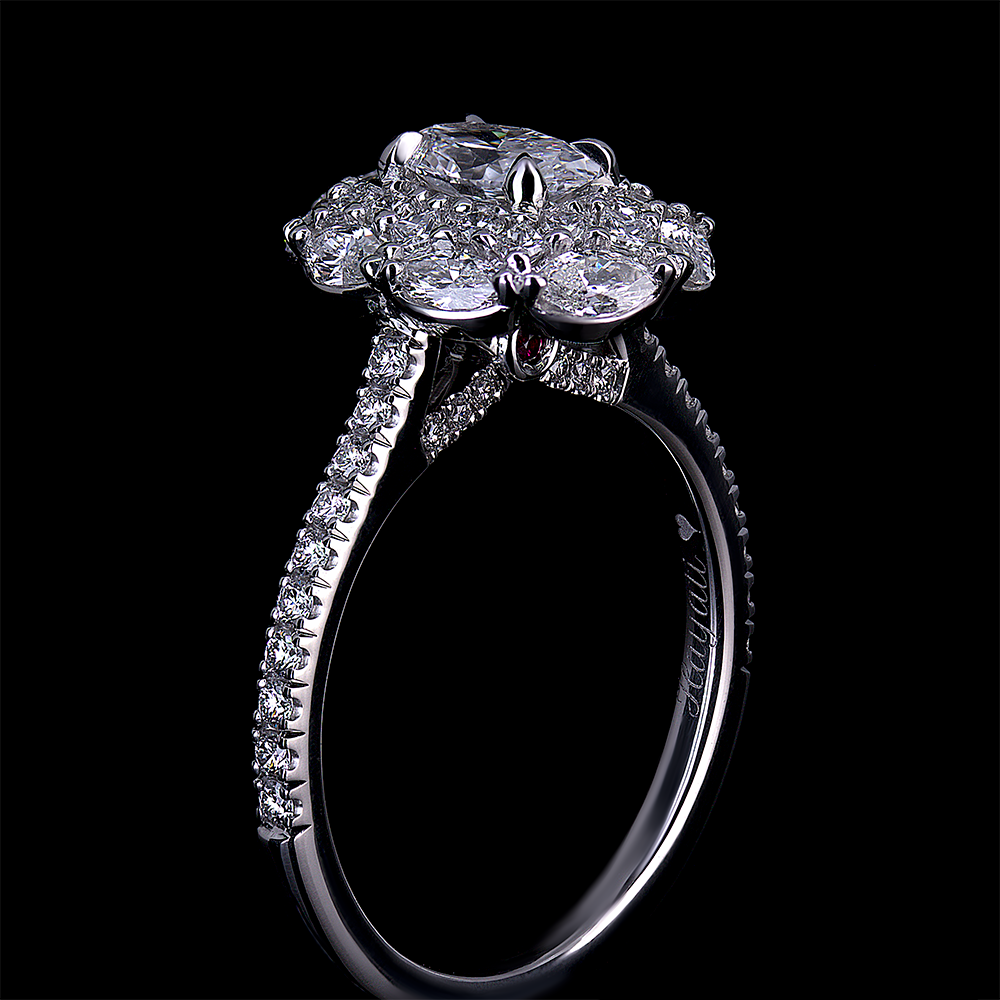 Side view of a platinum engagement ring with cluster halo. Featuring u-set round diamonds down the shank. U-set diamonds underneath the halo with a hidden bezel set ruby.