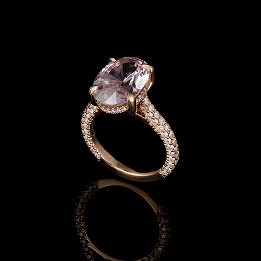 3 CT Oval pink sapphire center stone set in 4 talon claws. Accented by a hidden halo of diamonds in u-setting and a 3 sided pave shank. Made in a 18k rose gold mount.