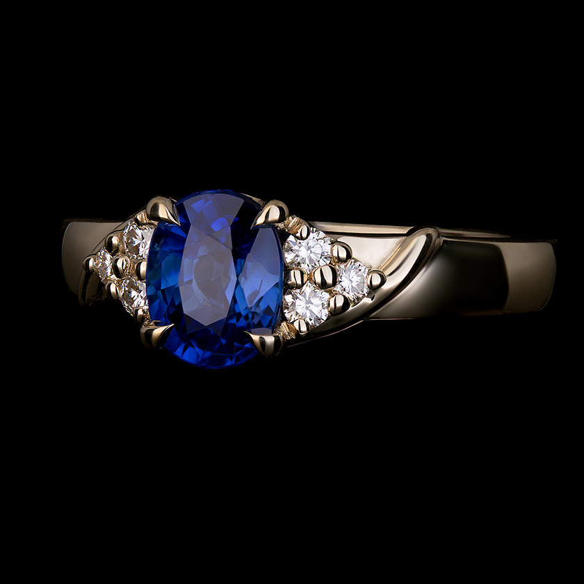 1.22 CT oval sapphire center stone, accented with three round diamonds on each shoulder in 14k yellow gold.