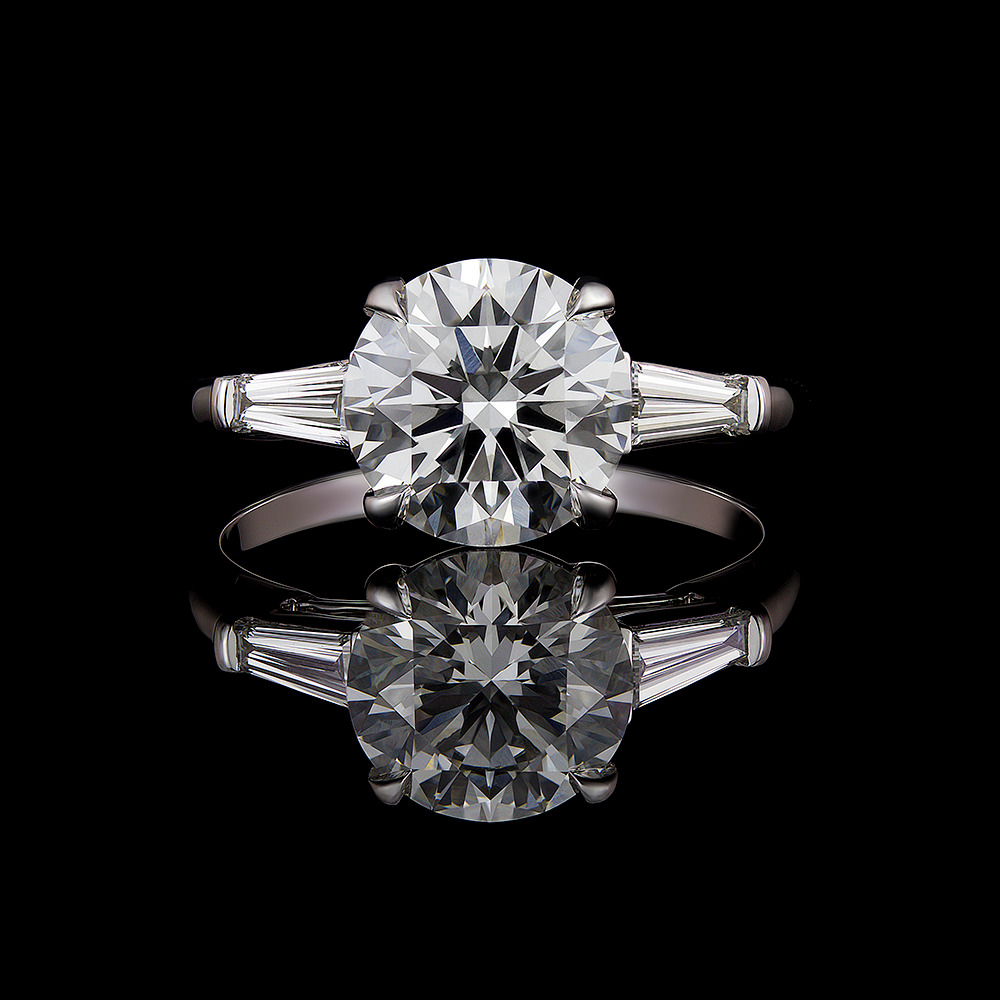 1.70 CT round diamond center stone accompanied by two matched tapered diamond baguettes in bar setting.