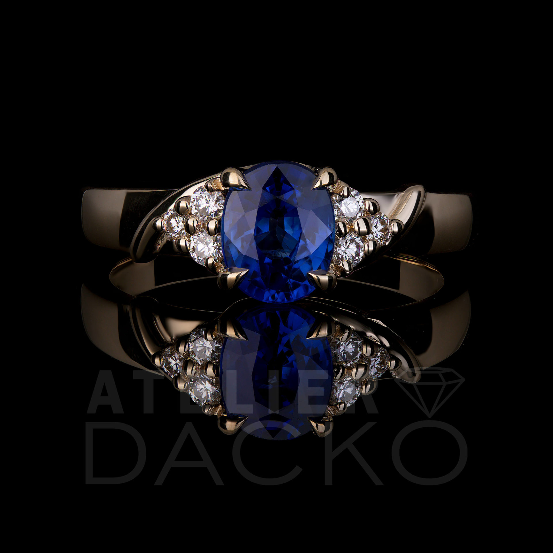 1.22 CT Ceylon blue oval sapphire center stone set in 14k yellow gold mount with 4 talon claws. Accented with 3 round diamonds on each shoulder set with round prongs.